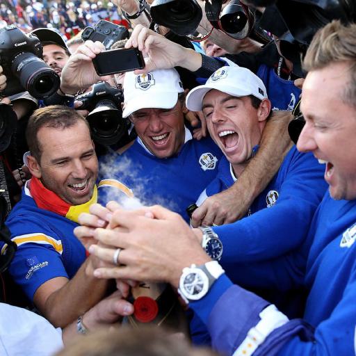 Eine Gruppe von Sportlern in blauer Kleidung wird von vielen Fotografen und Kameraleuten umringt.